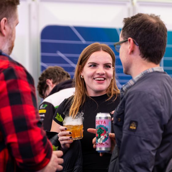 A woman drinking a pint, talking to a friend in The Arcade at Cheltenham Science Festival